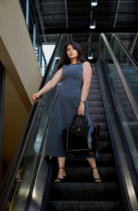 Woman holding a black Laurice Noire handbag on an escalator