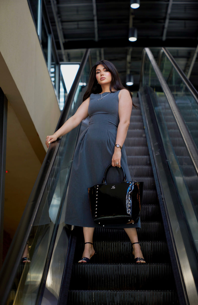 Woman holding a black Laurice Noire handbag on an escalator