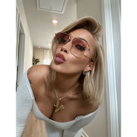 Woman wearing Laurice Noire Lenoah Rose Gold Polarized Sunglasses, posing with a playful kiss in a bright hallway.