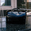 Black handbag on a reflective surface with blurred background