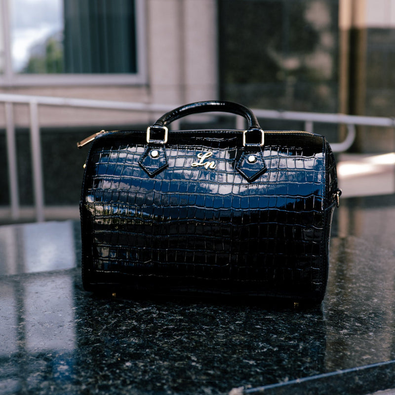 Black handbag on a reflective surface with blurred background