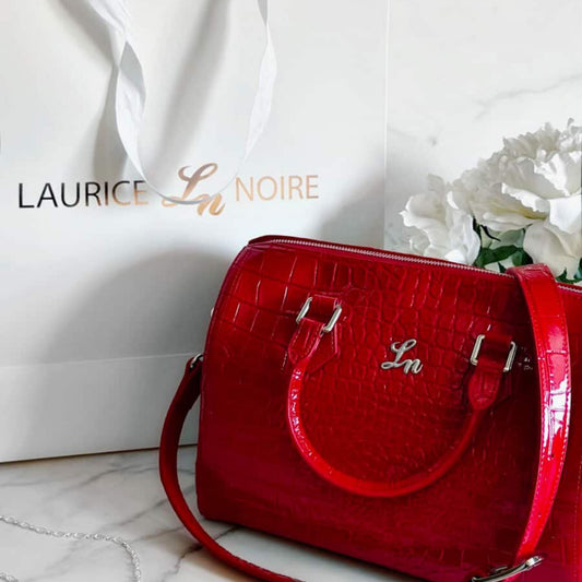Red handbag with 'Laurice Noire' branding on a white surface.