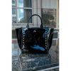 Black patent leather handbag with silver studs on a reflective surface