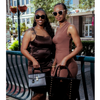 Two women in brown dresses standing outdoors with handbags.