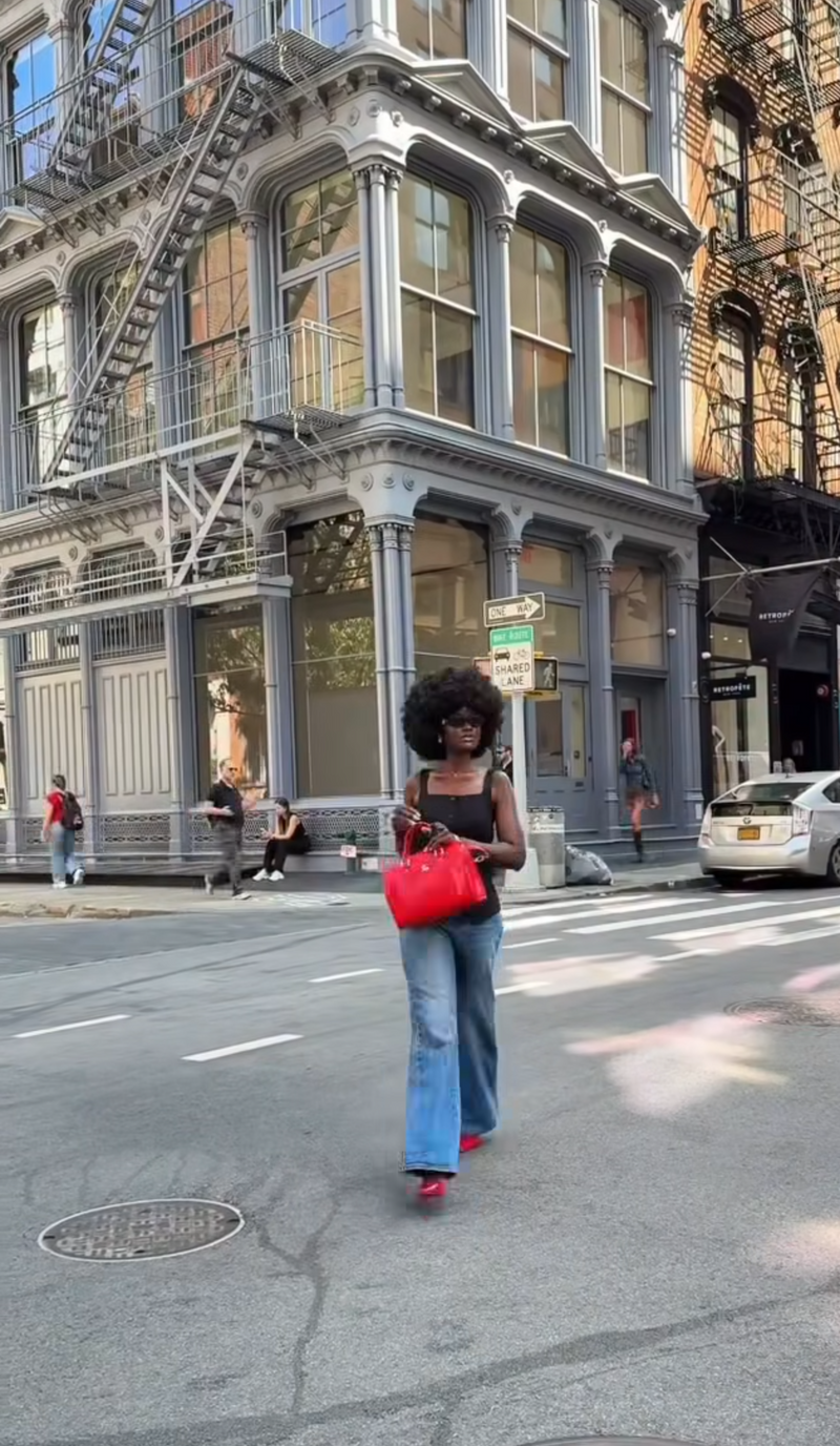 Woman walking on a city street with buildings and pedestrians in the background