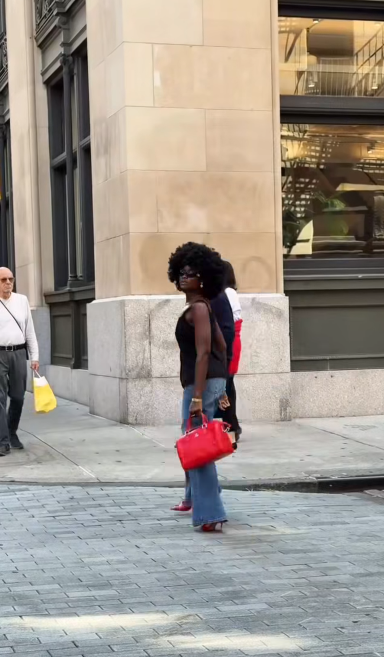 Woman walking on a city street holding a red handbag